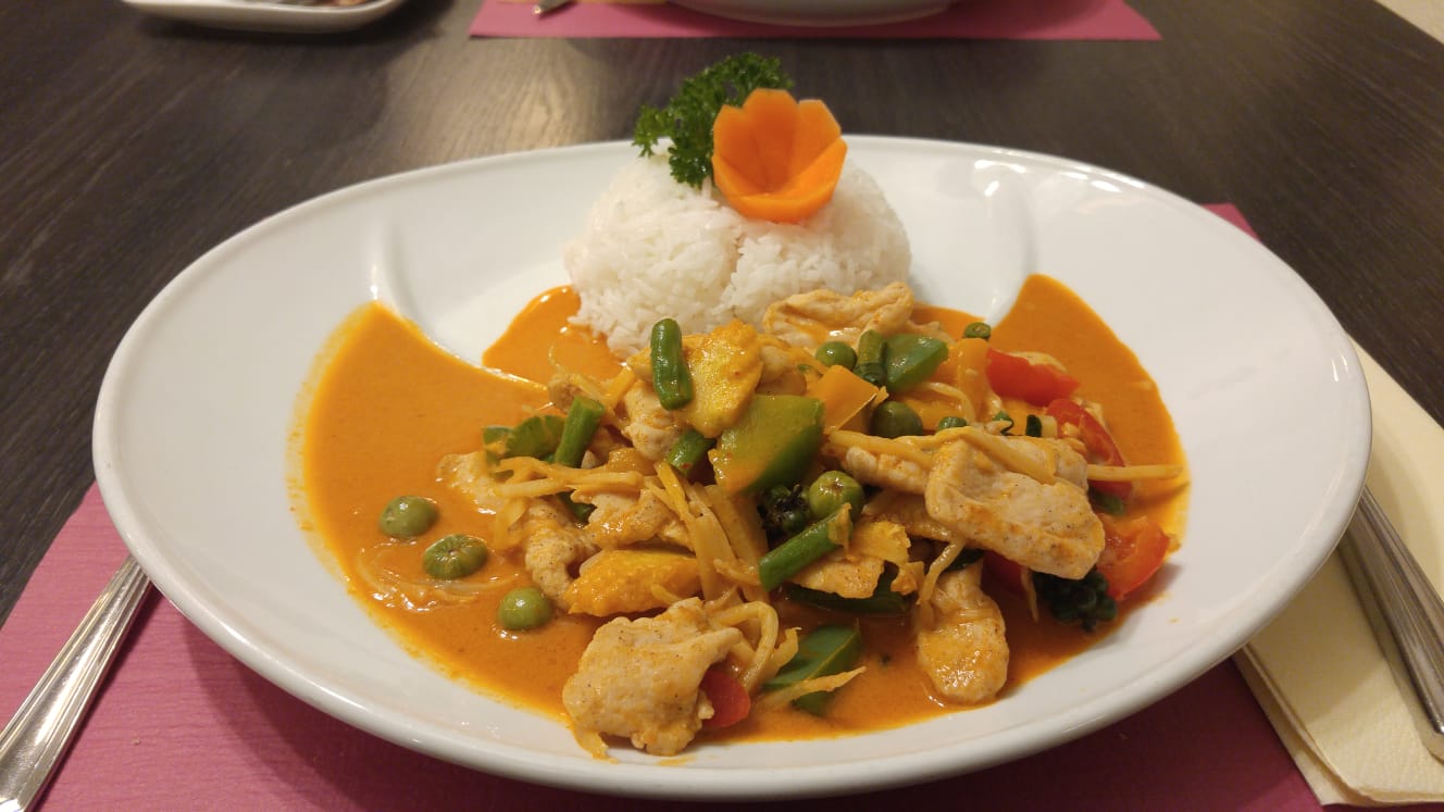 A decorative dish of chicken curry with jasmine rice on the side